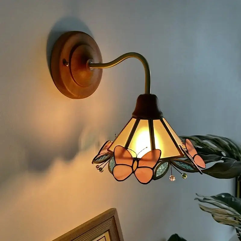 Antique brass wall light with copper arm and stained glass shade featuring orange and green decorbites butterfly glass motifs