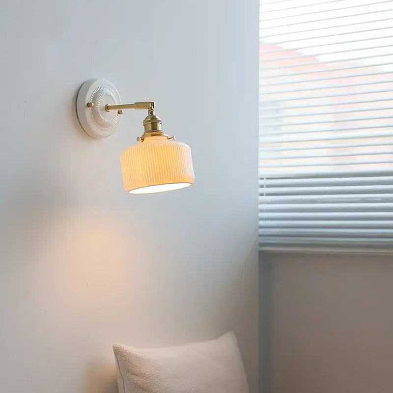 Vintage ceramic and brass wall sconce light with off-white ribbed glass shade and pull chain for bedroom use