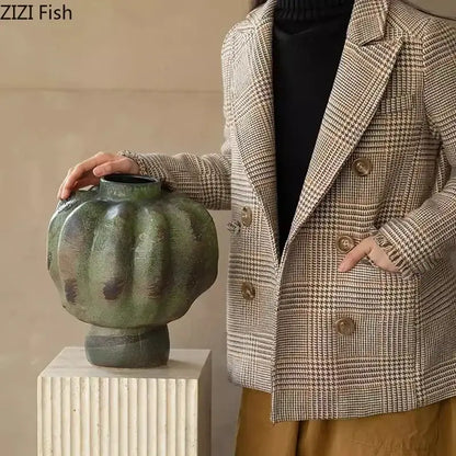 A rustic green vintage ceramic vase with textured pumpkin shape displayed on white pedestal for living room decorbites