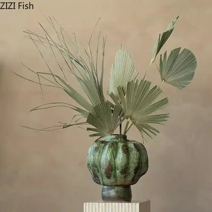 A green vintage ceramic pumpkin-shaped vase with fluted ridges holding dried fan palm decorbites green vintage
