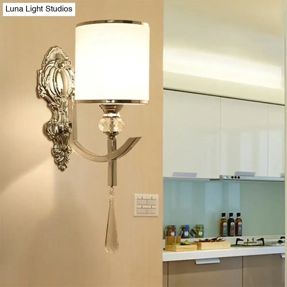 Elegant silver-toned vintage chrome wall sconce with carved backplate, ornate scrollwork, frosted glass, and crystal teardrop accent