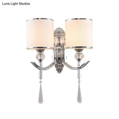 Vintage chrome wall sconce with carved backplate featuring silver ornate design, two cream fabric shades, and crystal droplets