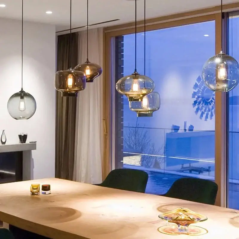 Modern colorful glass chandelier light with warm bulbs and black cords hanging above wooden dining table decorbites colorful glass
