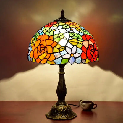 Vintage dragonfly tiffany stained glass table lamp with vibrant floral design in red orange yellow green and blue hues on bronze base