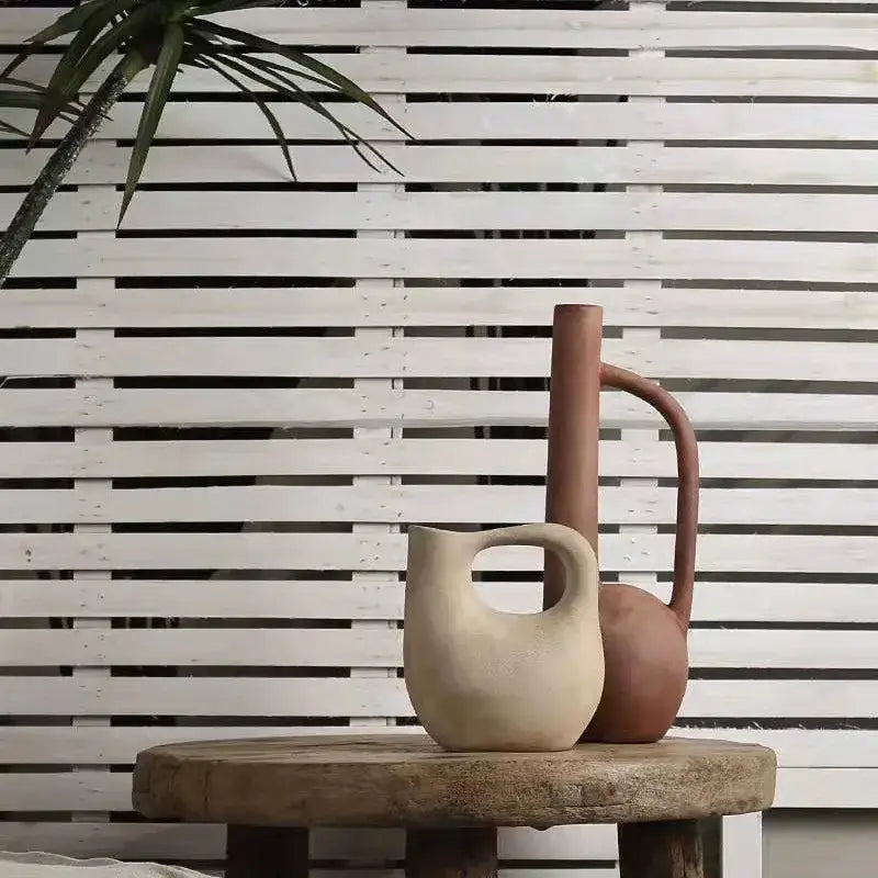 Two ceramic pitchers in beige matte and terracotta brown ceramic on a rustic table for decorbites geometric stoneware decor