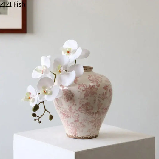 A blush-pink ceramic vase with vintage floral cracked texture blue and white porcelain decorbites cracked texture base holding white orchids