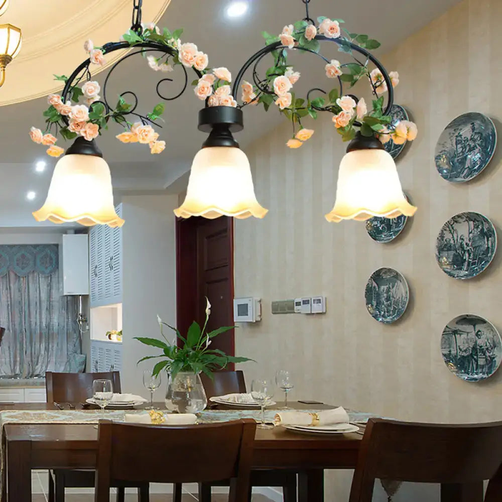 Black wrought iron chandelier with three frosted white glass shades and decorative pink roses for rose restaurant suspension