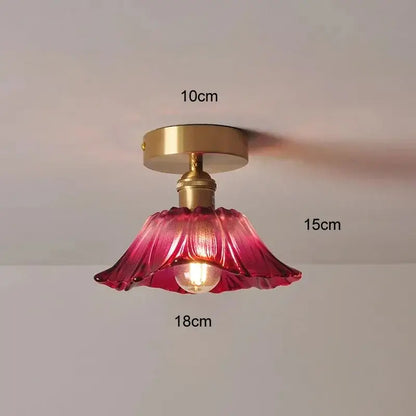 Delicate pink glass pendant light with ruffled petal edges and brass-finished mounting base for dining room use