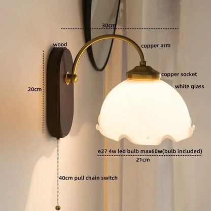 Antique brass-finished wall lights with scalloped white glass copper led shade and dark wood backplate for bedroom