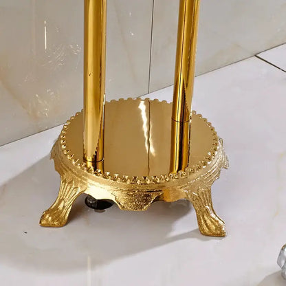 Golden ornate metal toothbrush holder with decorative base and three rods complementing vintage gold bath mixer tap