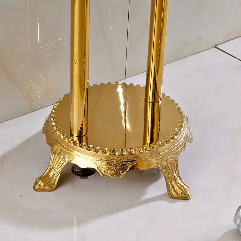 Golden ornate metal toothbrush holder with decorative base and three rods complementing vintage gold bath mixer tap