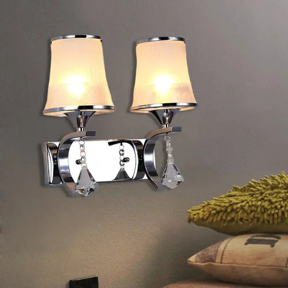 Chrome-finished wall lamp with two warm fabric shades and crystal teardrop pendants for elegant bedroom lighting