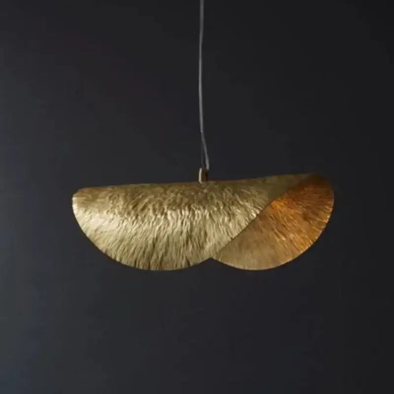 A modern gold metal pendant light with textured hammered leaf design and sculptural overlapping fan details for dining room