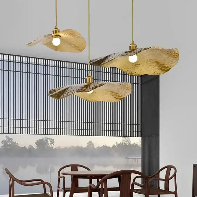 Three vintage gold metal pendant lights with hammered leaf design hang from ceiling for dining room lighting