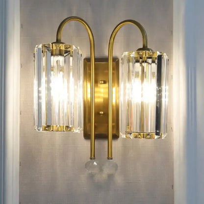 Brass-finished vintage gold wall light with two clear crystal shades and dangling glass orbs for bedroom use