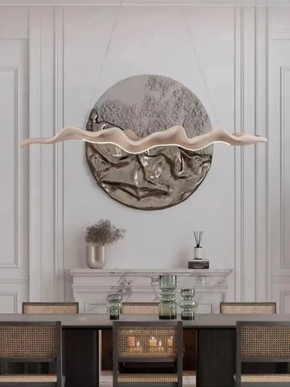 Vintage golden leaf iron finish pendant light with a modern wavy design and soft beige glow hanging above dining table
