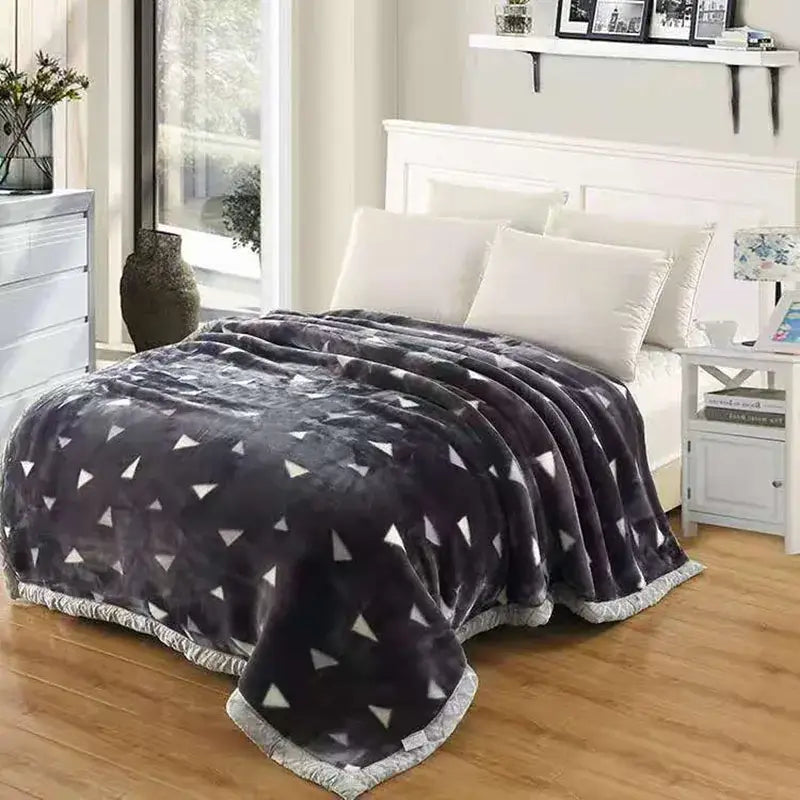 A plush dark gray double layered raschel blanket with white triangle pattern and matching fringed edge vintage style throw