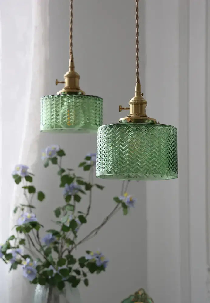 Two hanging green glass shade chandelier pendant lights with textured chevron pattern and brass fixtures for dining room