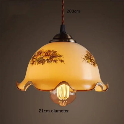 A warm amber glass vintage pendant lamp with floral design and scalloped edge featuring brass hardware