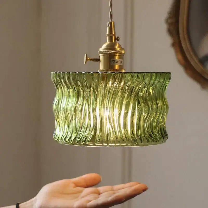 Vintage green glass pendant light with wavy texture and brass fixture designed for dining room use