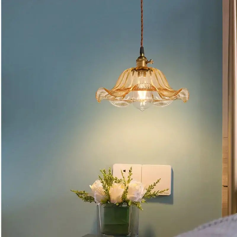 A vintage glass pendant light with a golden metal frame and petal design for cafe and restaurant lighting