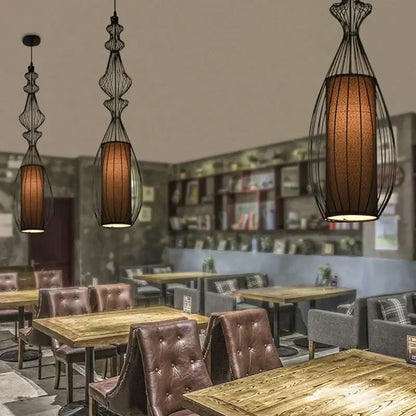 Vintage industrial black birdcage chandelier with warm amber fabric shades hangs above wooden dining tables decorbites birdcage chandelier