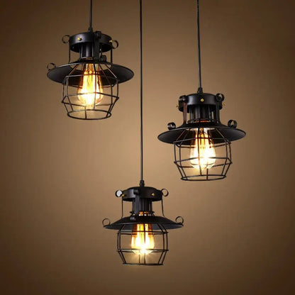 Three vintage industrial black metal pendant lights with cage frames and exposed filament bulbs for kitchen use