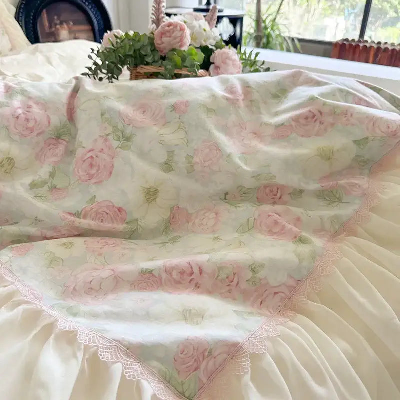 A cream cream-colored bedding set with soft pink roses green foliage and lace-trimmed decorbites french lace ruffles
