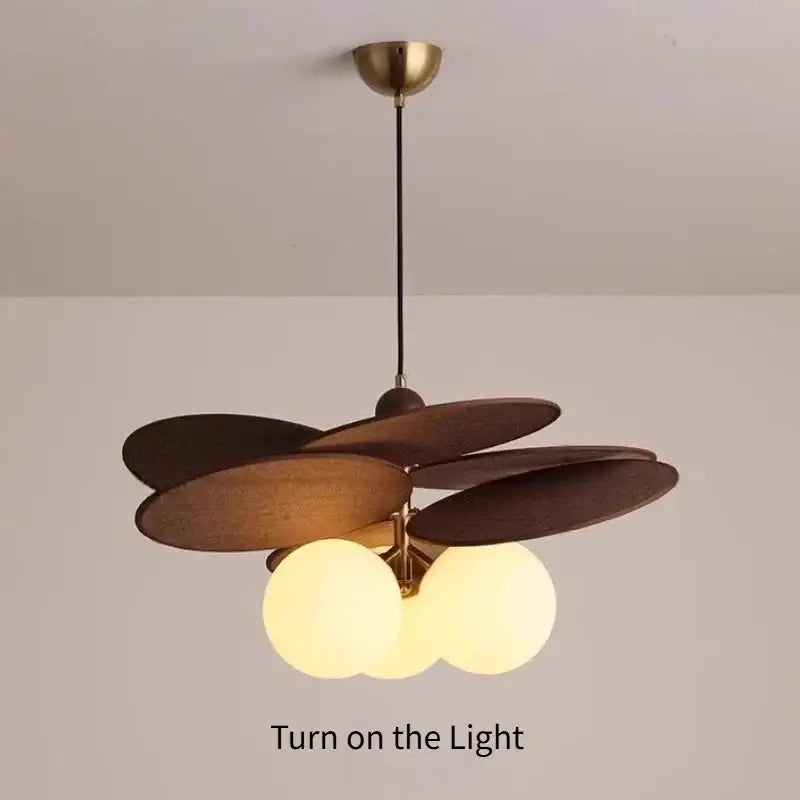 A vintage layered wood petal pendant light with brass ceiling mount, black cord, and three frosted globe bulbs