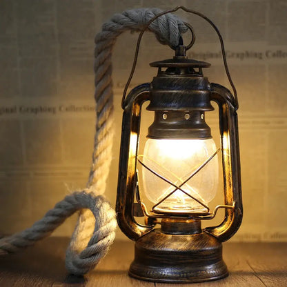 Vintage mixed metal cage pendant light with brass lantern, warm glowing bulb, and rope handle for decorative presence