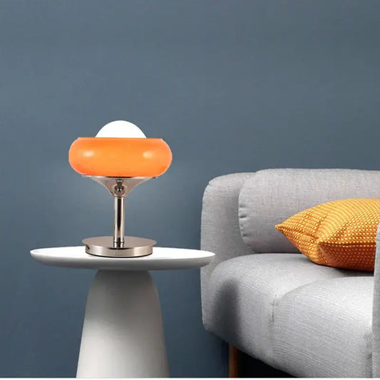 Vintage orange glass and chrome table lamp with white spherical bulb on a minimalist white side table for bedroom lighting