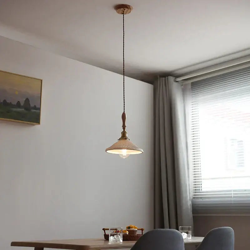 A warm-toned brass decorbites ceramic led pendant light with wooden ceiling fixture and textured cream ribbed glass shade
