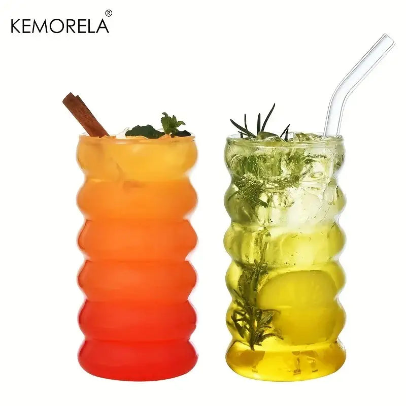 Two kemorela tall ribbed glass tumblers with wave shape beverage design filled with layered colorful drinks and herbs
