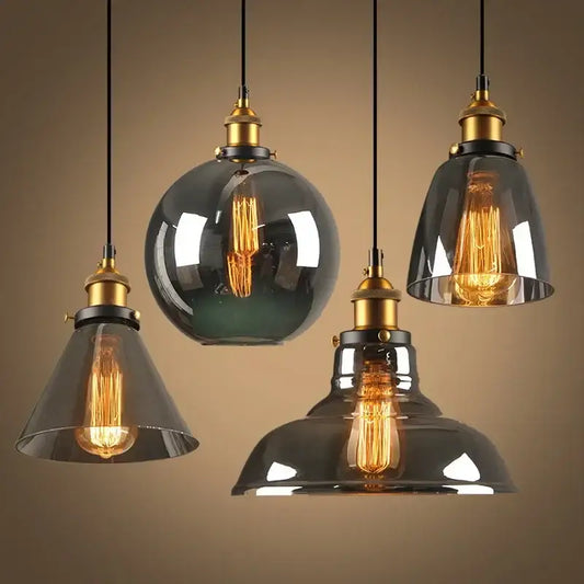 Set of four vintage pendant lights with amber glass shades and brass fixtures featuring exposed filament bulbs