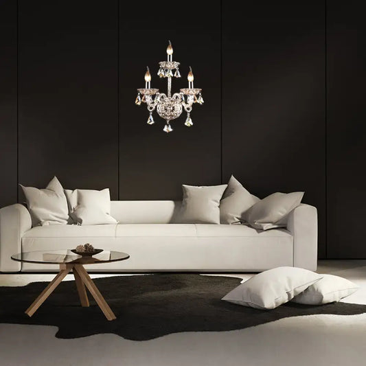 A vintage style amber crystal candle wall light with sparkling droplets hangs above a minimalist white sofa