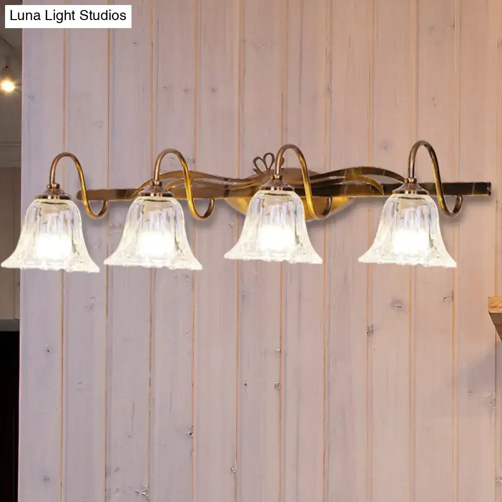 Vintage style wall light with brass finish and four clear bell-shaped glass shades for bathroom vanity use