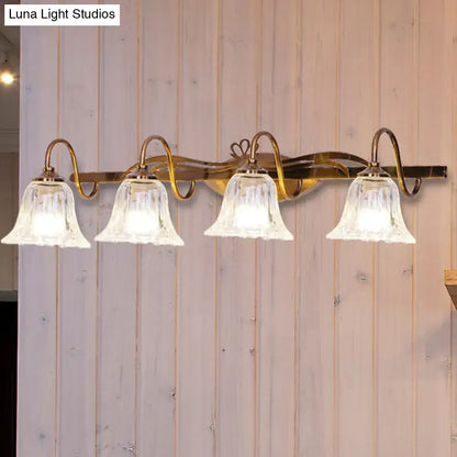 Vintage style wall light with brass finish and four clear bell-shaped glass shades for bathroom vanity use