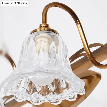 Vintage style wall light featuring a clear intricately cut glass bell-shaped lampshade with a gold brass frame and curved arm
