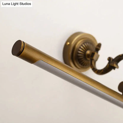Vintage style gold metallic tubular wall light with antique brass finish and ornate bracket for bathroom vanity