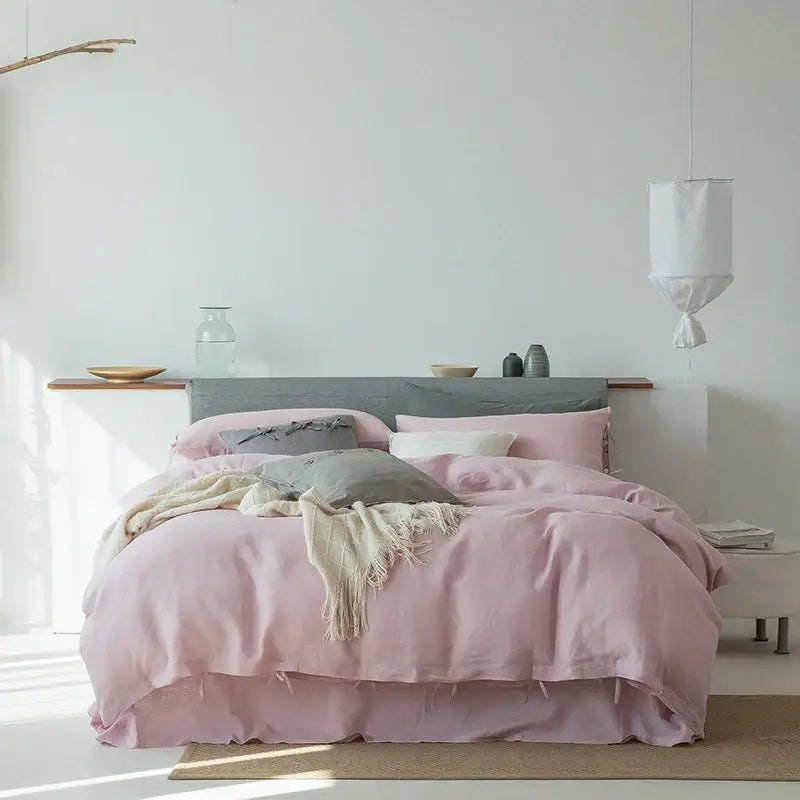 Vintage white and gray linen bedding set featuring a soft pink linen duvet with matching skirt and layered pillows in gray white and blush