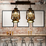 Two vintage-style brass lanterns with warm glow hang from wood beam in decorbites copper lantern island light fixture
