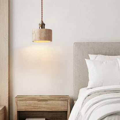 A beige cylindrical concrete pendant light with a warm glow and dark brown braided cord for dining room decorbites led yellow travertine