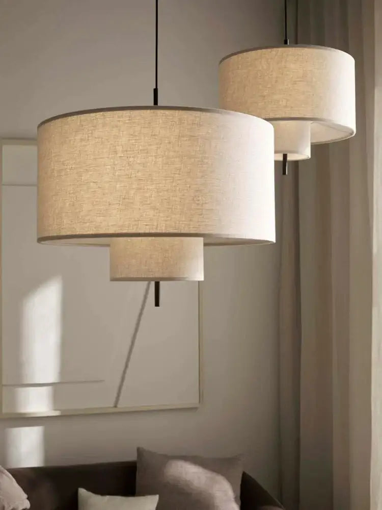Beige linen cylindrical pendant lamps with black cords for dining room decor by decorbites bohemia wabi sabi
