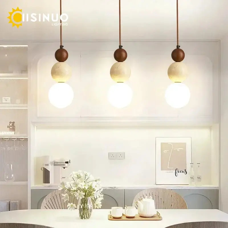 Three modern beige stone pendant lights with wooden accent tops and dark cord pendant for dining room lighting
