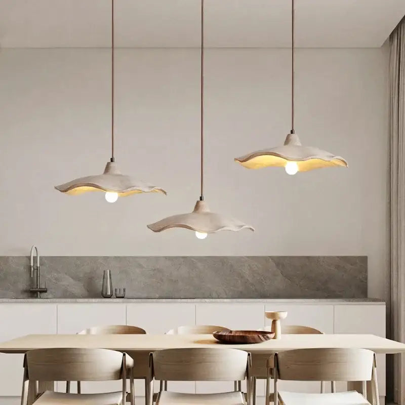 Three elegant off-white ceramic pendant lights with scalloped edges and natural wood material for dining room