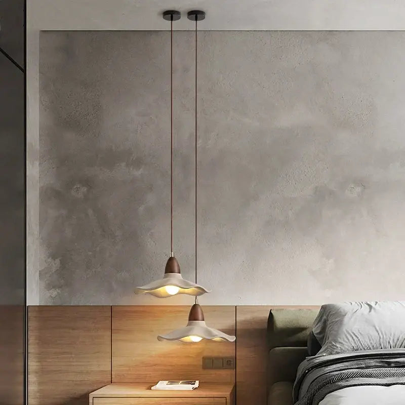 Two minimalist pendant lights with matte white petal-shaped shades and dark brown natural wood tops for dining room