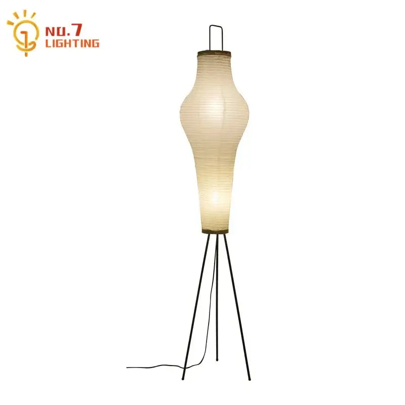 A tall slender wabi-sabi tripod floor lamp with a cream paper shade and black metal base for living room decor