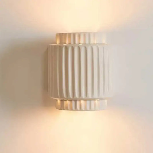 Cream white resin wall lamp with vertical fluted ridges and warm diffused glow for bedroom lighting
