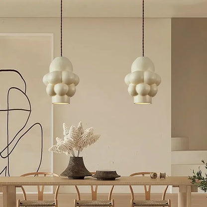 Off-white creamy wind led chandelier with matte cloud-shaped pendants hanging above dining table by decorbites