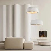 Two modern wabi sabi textured white ceramic led pendant lights hang emitting a warm glow for dining room use